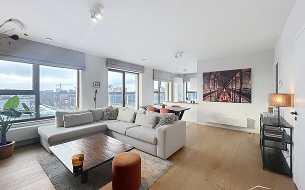 Verzorgd volledig ingericht hoekappartement op de 8e verdieping met een open uitzicht op het MAS en over de Leie. Inkomhal met vestiairekast en apart toilet. Ruime woon- en eetkamer op parketvloer (ca. 36m&sup2;) welke toegang geeft tot het overdekte terras. 