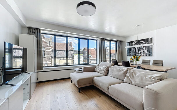 In een kleinschalig en verzorgd gebouw met lift bevindt zich dit prachtig gerenoveerde appartement met hoogwaardige afwerking. De ruime inkomhal beschikt over een bergkast met aansluiting voor wasmachine en droogkast. De lichtrijke woonkamer met grote ram