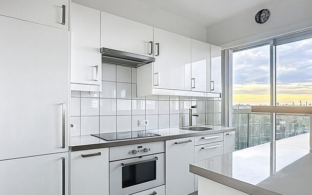 Dit lichtrijke appartement op de 14de verdieping biedt een uniek panoramisch uitzicht over de skyline van Antwerpen. Bij binnenkomst word je verwelkomd in een ruime inkomhal met praktische maatkast en directe toegang tot alle ruimtes.

De gezellige woonka