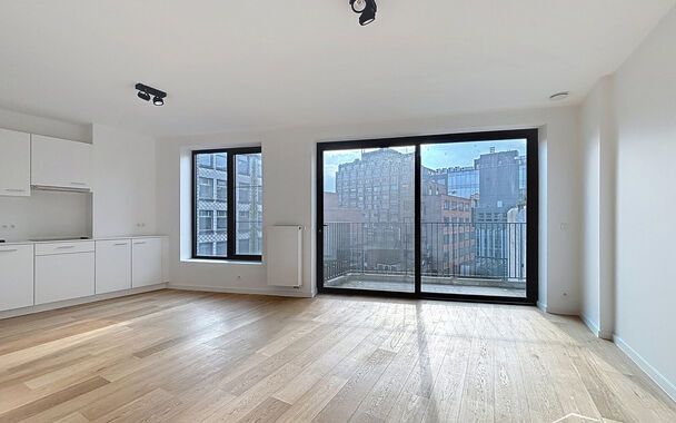 Het appartement bevindt zich op de zesde verdieping, achteraan in residentie KPlaza, een modern, energiezuinig en stijlvol nieuwbouwproject dat werd opgeleverd in 2019. Bij het betreden van de leefruimte valt meteen de mooie parketvloer op, evenals de kwa