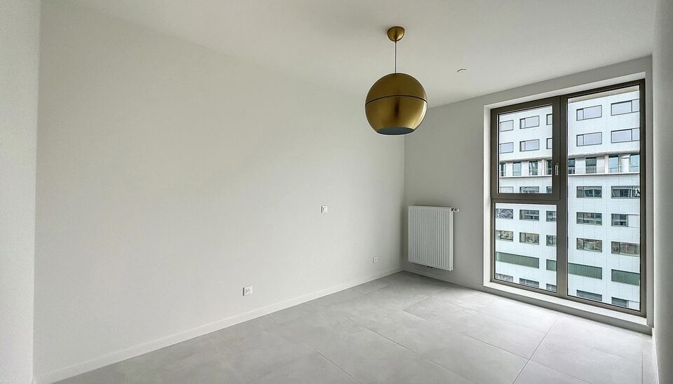 Luxe nieuwbouw appartement op de 20e verdieping met 270 graden uitzicht over Antwerpen, Park Spoor Noord, het Eilandje en de dokken. De lichtrijke leefruimte (ca. 26 m&sup2;) met open  keuken (ca. 6 m&sup2;) is voorzien van een keramische kookplaat, dampkap, koel