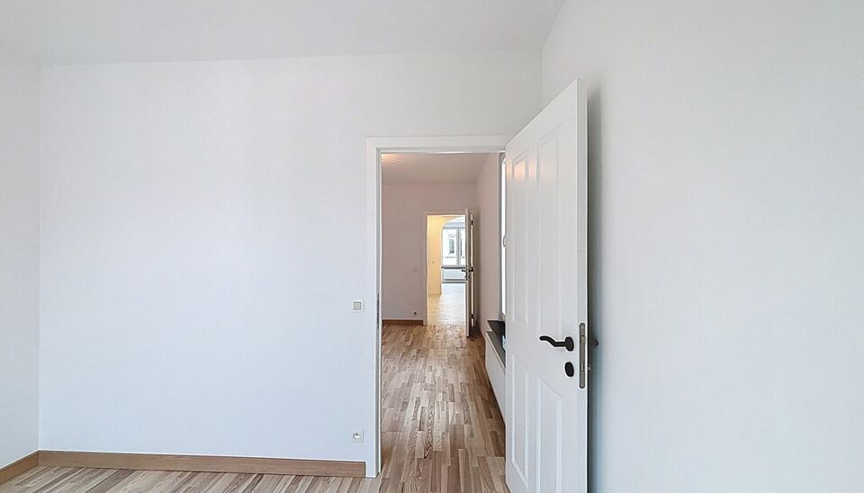 Bij het betreden van dit volledig gerenoveerde appartement wordt u verwelkomd in een stijlvolle inkomhal met een elegante, afgeronde deuropening.
Direct aan de inkom bevindt zich een bureauruimte met parketlaminaat en een gloednieuw raam, ideaal voor thui