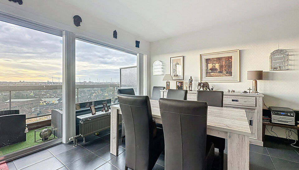 Dit lichtrijke appartement op de 14de verdieping biedt een uniek panoramisch uitzicht over de skyline van Antwerpen. Bij binnenkomst word je verwelkomd in een ruime inkomhal met praktische maatkast en directe toegang tot alle ruimtes.

De gezellige woonka