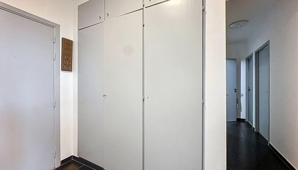 Dit lichtrijke appartement op de 14de verdieping biedt een uniek panoramisch uitzicht over de skyline van Antwerpen. Bij binnenkomst word je verwelkomd in een ruime inkomhal met praktische maatkast en directe toegang tot alle ruimtes.

De gezellige woonka