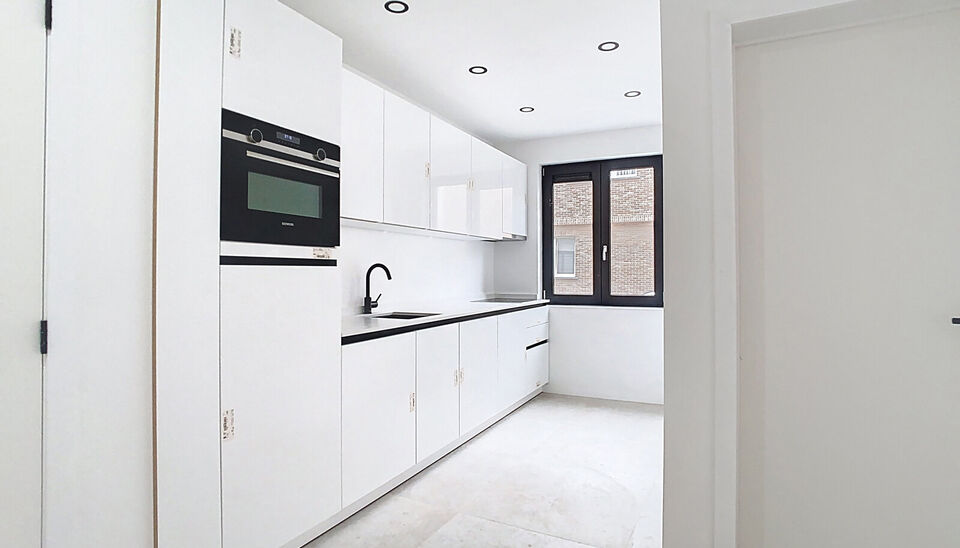 Stap binnen in dit smaakvol afgewerkte appartement, gelegen in een klassevol gerenoveerd gebouw op wandelafstand van het centrum van Edegem.
De inkomhal biedt directe toegang tot de moderne keuken, volledig uitgerust met hoogwaardige Siemens-toestellen 