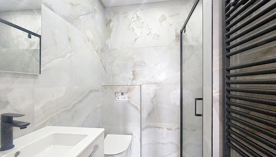 Stap binnen in dit smaakvol afgewerkte appartement, gelegen in een klassevol gerenoveerd gebouw op wandelafstand van het centrum van Edegem.
De inkomhal biedt directe toegang tot de moderne keuken, volledig uitgerust met hoogwaardige Siemens-toestellen 